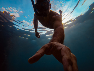 Man snorkeling underwater and reaching hand