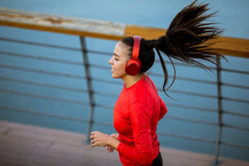 Active young beautiful woman running on the promenade along the riverside