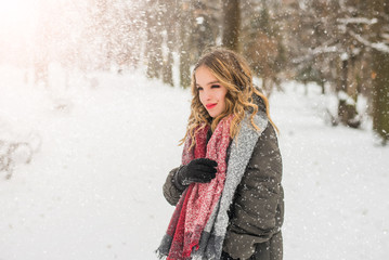 Christmas, New Year, winter holidays concept. Cute teenage girl with curly hair. playing with snow in park.