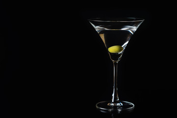 Martini glass and olives on a black background. Selective focus. Close up.