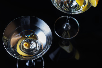 Martini Glasses with olive and lemon piece  on a black background. Selective focus. Close up.