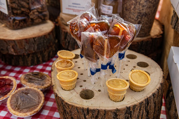 Obraz na płótnie Canvas Sweet treats at local farmer's market. A closeup view of handmade lollipops and confectionary displayed in rustic wooden stands on a market stall during a fair for local cottage industries.