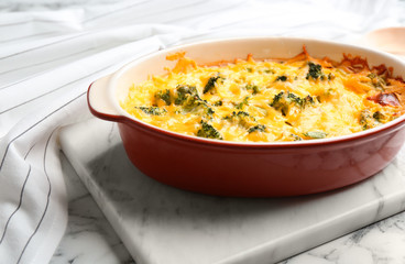 Tasty broccoli casserole in baking dish on white marble table