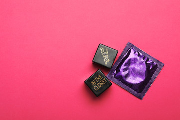 Sex dice and condom on pink background, top view. Space for text