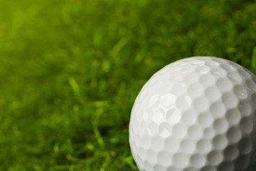Golf ball on green course outdoors, closeup. Space for text