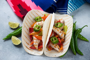 Tortillas filled with freshly made tex-mex fajitas, studio shot over light-blue stone background