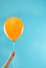 Woman holding orange balloon for Halloween party on blue background