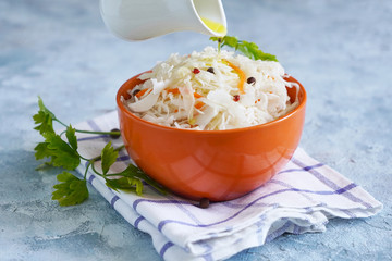 Cook sprinkles olive oil on sauerkraut in a bowl. Healthy probiotic food