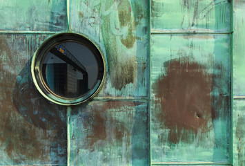 Vintage single round porthole window with reflection of a traffic sign. Green patina - natural...
