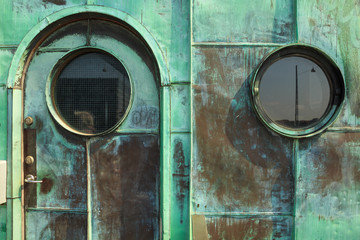 Two round windows and the entrance door. Green patina - natural oxidation of copper surface on sheets used for facade cladding. Vintage control tower on Long bridge (Langebro) in Copenhagen, Denmark.