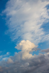 White clouds of different shapes in blue sky, vertical format_