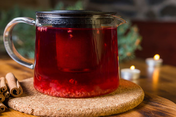 Hot raspberry tea with spices in a glass teapot. Health fresh fruit drink. Enjoying hot beverage in cold winter christmas eve.