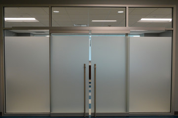 a neat and clean office space with a modern glass doorframe