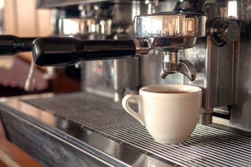 Fototapeta na wymiar Cup of coffee under the nozzle of a coffee machine