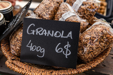 Fresh food at outdoor farmer's market. Healthy bags of granola are seen close up, displayed in a wicker basket with a price sign, selling food by weight at an outdoor biological market.