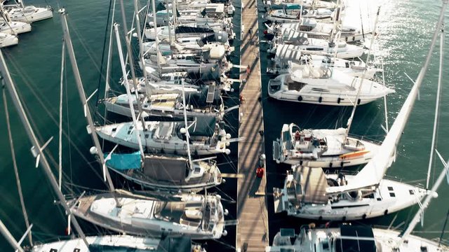 Low altitude aerial down view of a marina pier and many docked sailing yachts