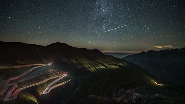 Passo dello Stelvio - Stelvio pass in Italy, Ortler Alps, Italy - curvy road with cars and light trails through mountains at night with starry sky