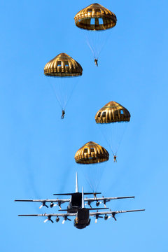 Group of military parachutist paratroopers jumping out of a military transport plane.