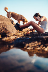 Girl and her dog exploring rocky beach