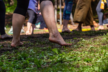Diverse people enjoy spiritual gathering A ground level perspective on an intergenerational group of people, standing barefooted on grass and soil as they celebrate native cultural dance in nature.