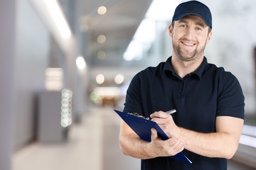 Delivery man with clipboard on light background