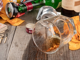 Morning after a booze. On the table are bottles of beer, spilled whiskey.