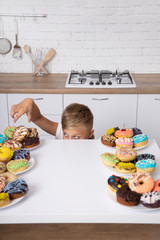 The boy reaches for Donuts. A lot of donuts.