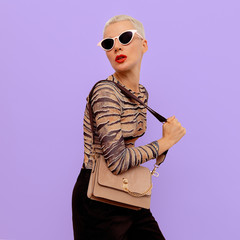 Stylish model in fashion accessories sunglasses and clutch. Accent for beige and animal print