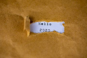 The text, hello 2020, appears behind torn brown paper