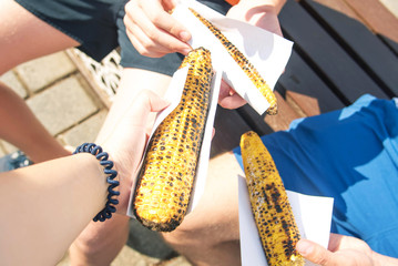 Charcoal grill sweet corns. corn cooked in barbecue barbecued corn on the roaster. Corn in hand