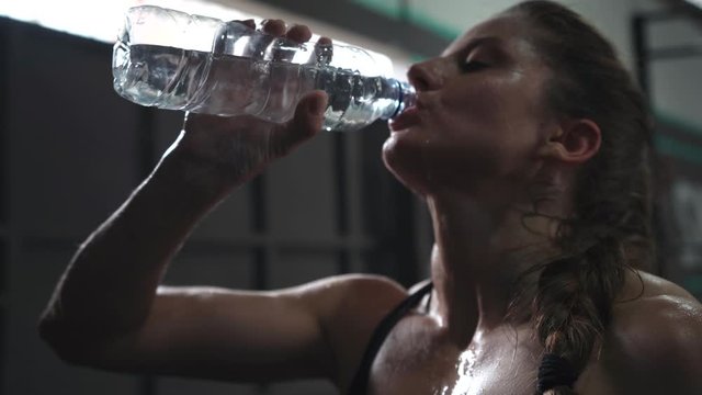  sporty beautiful woman eagerly drinking water from a bottle after training in the gym