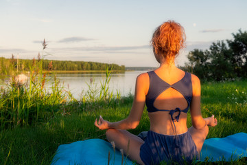 Young woman practicing yoga on the beach at sunset