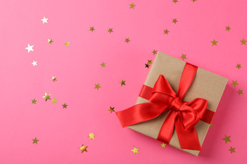 Fototapeta premium Gift box with bow on decorated pink background, space for text