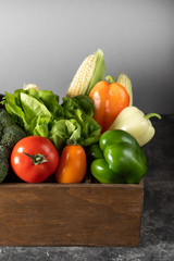 Fresh vegetables in a wooden box on a dark wooden background.