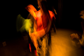Woman performing techno trance dance seen with slow shutter speed and thus in motion blur.