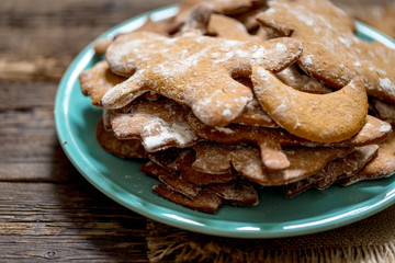 Homemade Decorated Gingerbread Men Cookies for Christmas on a plate on rustic aged wooden table.