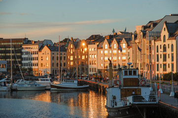 sun reflection on buildings facades at nordic sunset in Alesund marina on the fjord