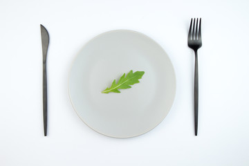 Arugula leaves on a gray plate. The concept of proper and dietary nutrition.