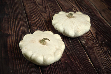 Two white pattypan squash on dark wooden board