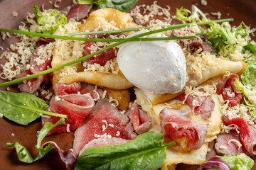 Diet menu. Salad with chopped steak, poached eggs, pancakes, green salad. Sprinkled with grated cheese.