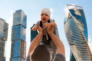 Father and one year old son against the sky and skyscrapers. Travel with children, the development of emotional intelligence. Early development.