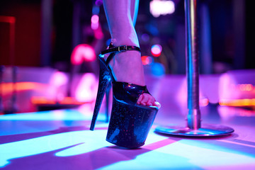 Young sexy woman pole dancing striptease with pylon in night club. Beautiful naked stripper girl on...
