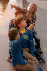 Mom with three children in the park. Two twin teens and a 5 year old boy. Look at interesting things. Training. A comfortable pastime with family.