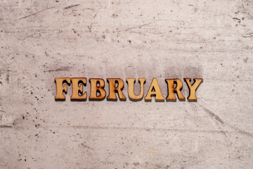 The word February laid out in wooden letters on a light background. Close-up. Summer time years and months of the year.
