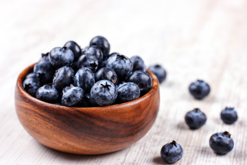 Fresh blueberries in a wooden bowl on white table