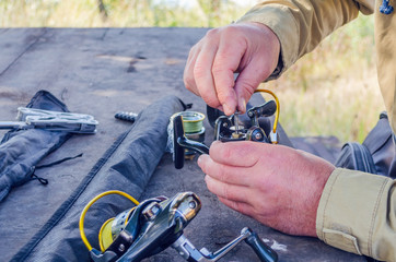 a man repairs a fishing reel with improvised means - Powered by Adobe