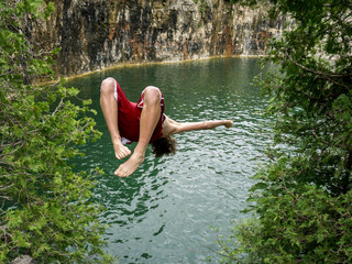 Teenagers jumping off a cliff into a lake.