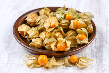 Physalis on a clay dish. Ripe berries of autumn physalis fruit