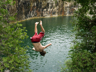 Teenagers jumping off a cliff into a lake.