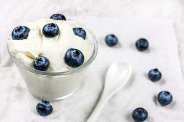 Diet yogurt with large fresh blueberries. White unsweetened yogurt in a glass